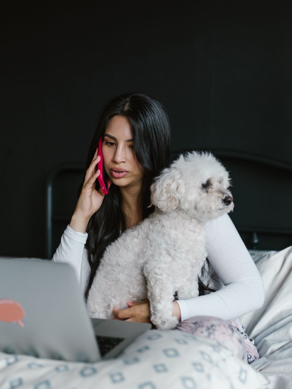 A pet parent on the phone with her dog in her lap